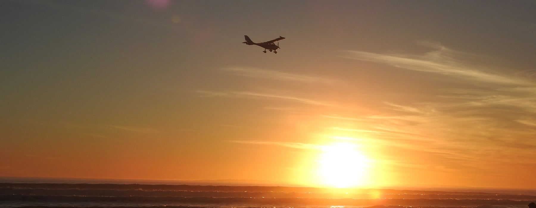 Aircraft flying towards sunset